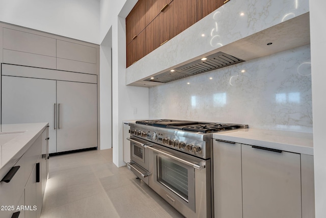 10354 E Celestial Dr, Scottsdale, AZ 85262 - kitchen featuring high quality appliances, modern cabinets, decorative backsplash, wall chimney exhaust hood, and light stone countertops