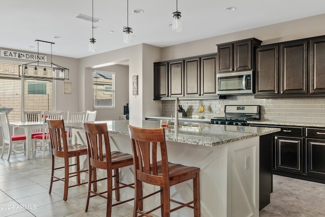 kitchen with pendant lighting, a kitchen breakfast bar, appliances with stainless steel finishes, and a kitchen island with sink