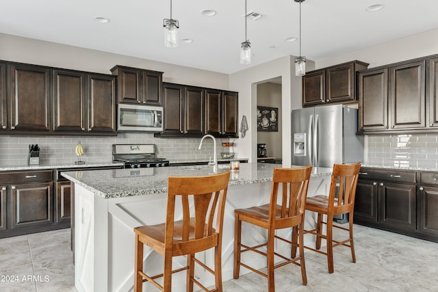 kitchen featuring an island with sink, a kitchen breakfast bar, dark brown cabinetry, and stainless steel appliances