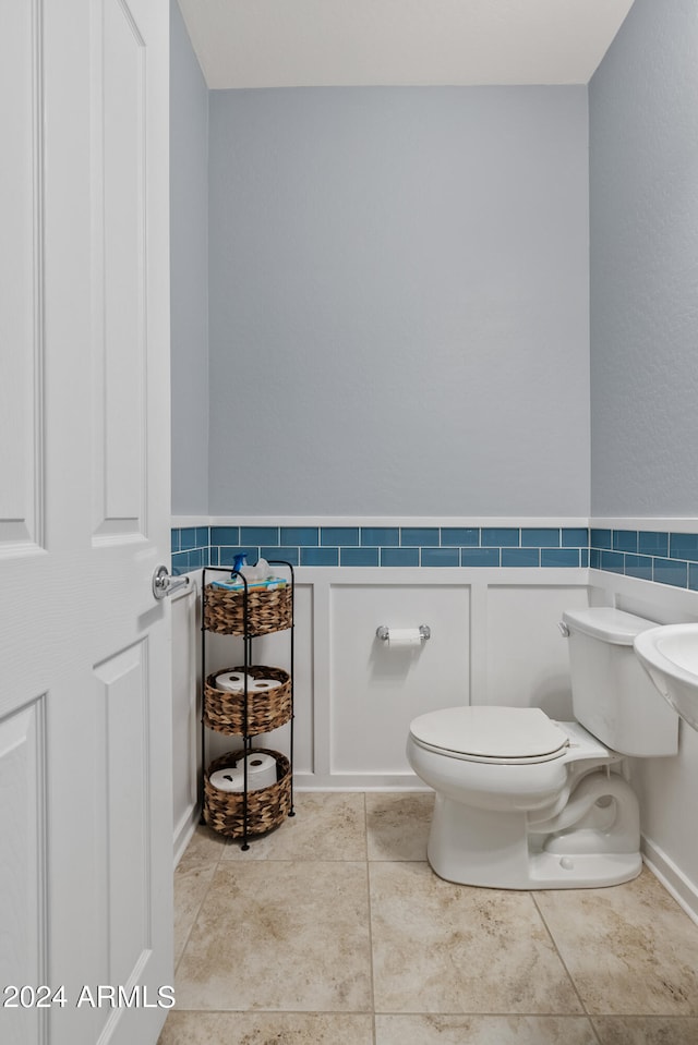 bathroom with tile patterned flooring, tile walls, and toilet