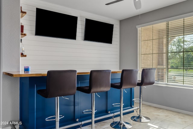 interior space featuring ceiling fan, light tile patterned floors, and butcher block counters