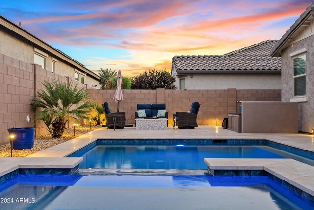 back house at dusk with a pool with hot tub and a patio area