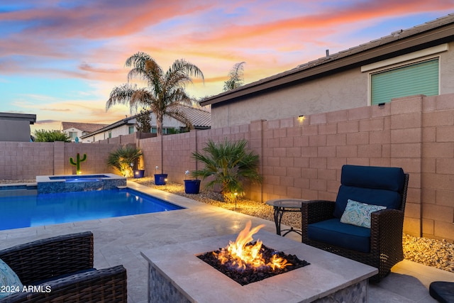 pool at dusk featuring a fire pit, a patio, and an in ground hot tub