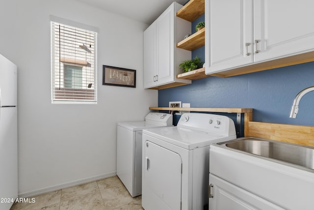 laundry area with light tile patterned floors, cabinets, sink, and independent washer and dryer