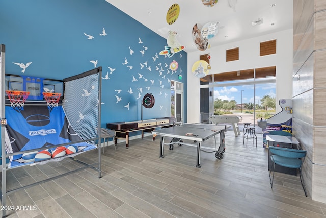 game room with a towering ceiling and hardwood / wood-style floors