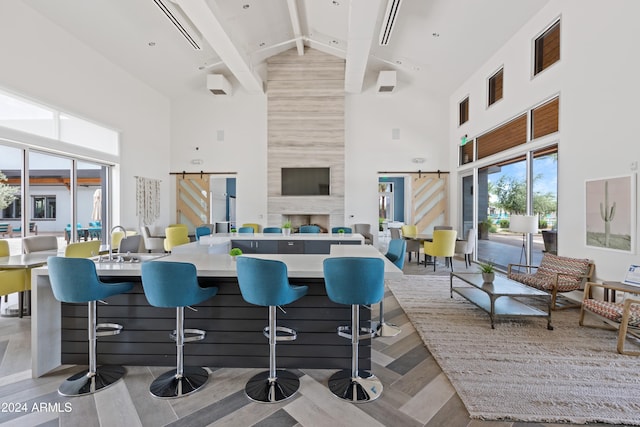 kitchen featuring a barn door, high vaulted ceiling, beam ceiling, and a kitchen breakfast bar