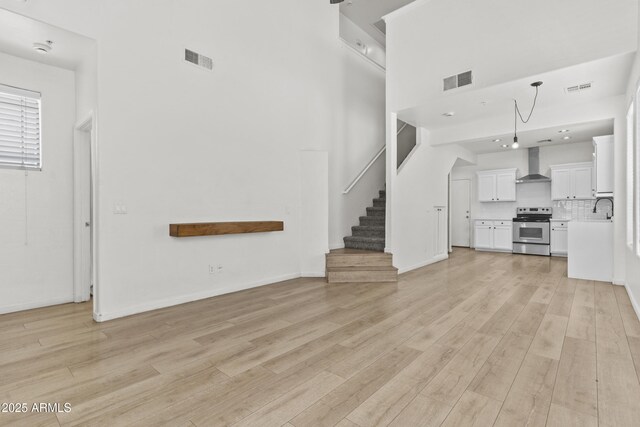1225 N 36th St Unit 1015, Phoenix, AZ 85008 - unfurnished living room featuring light wood-style floors, a sink, stairway, a high ceiling, and baseboards
