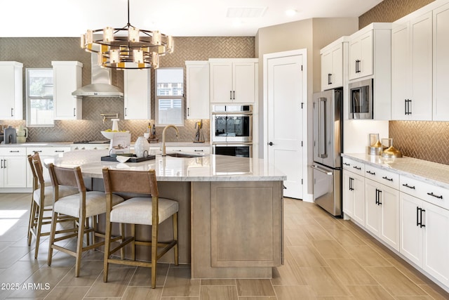 kitchen featuring stainless steel appliances, light stone counters, and an island with sink