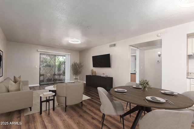 dining room with visible vents, a textured ceiling, baseboards, and wood finished floors