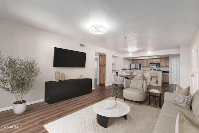 living room featuring visible vents, baseboards, and dark wood finished floors