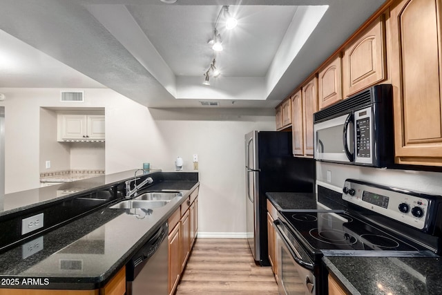 kitchen featuring dark stone countertops, visible vents, light wood finished floors, a sink, and appliances with stainless steel finishes