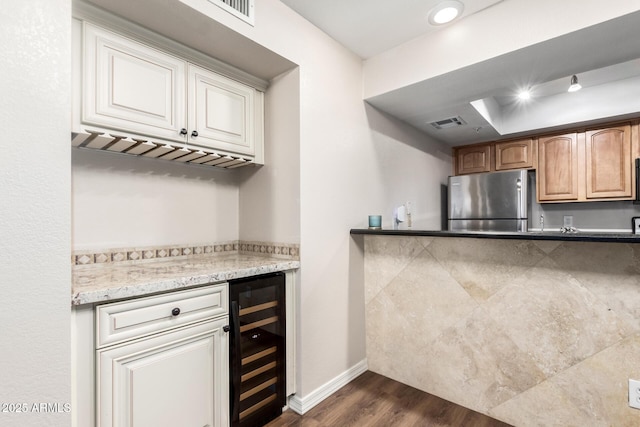 kitchen with visible vents, beverage cooler, dark wood finished floors, freestanding refrigerator, and baseboards