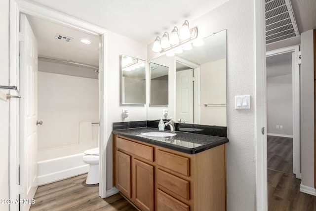 bathroom with vanity, toilet, wood finished floors, and visible vents