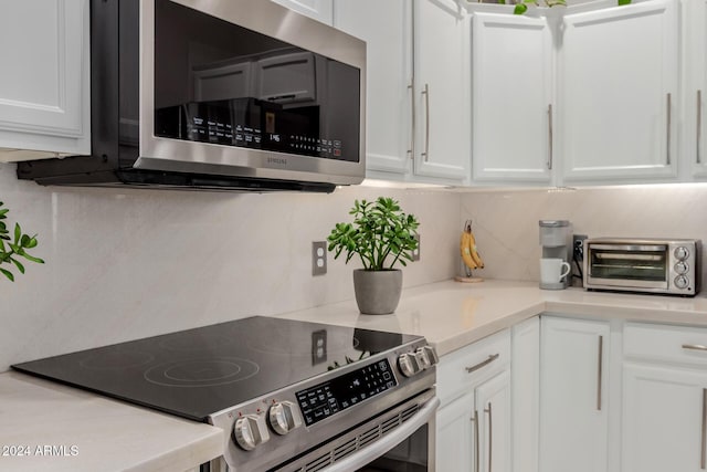 kitchen with tasteful backsplash, white cabinetry, and stainless steel appliances