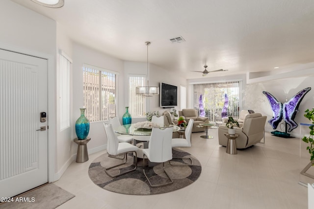 tiled dining area with a wealth of natural light and ceiling fan with notable chandelier