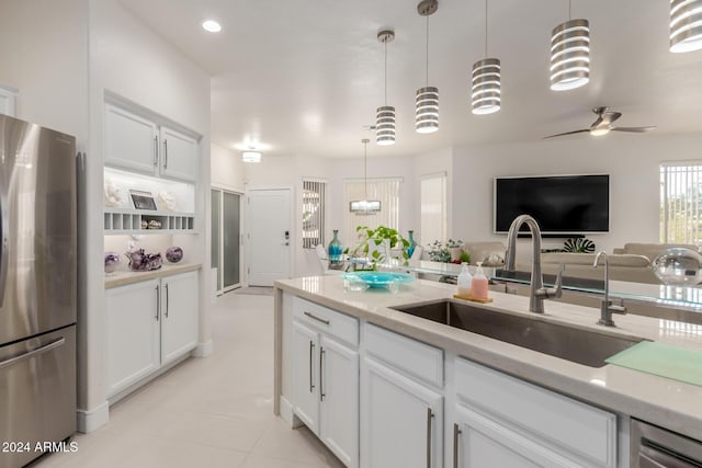 kitchen featuring white cabinets, ceiling fan with notable chandelier, sink, hanging light fixtures, and stainless steel fridge