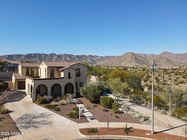 exterior space with driveway, a tile roof, a mountain view, and stucco siding