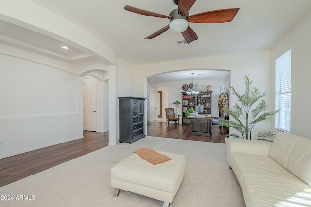 living room with ceiling fan with notable chandelier, arched walkways, visible vents, and wood finished floors