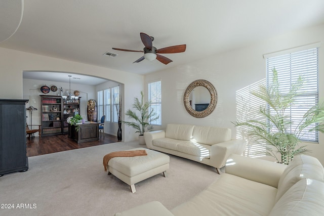 living area featuring arched walkways, ceiling fan with notable chandelier, wood finished floors, and visible vents