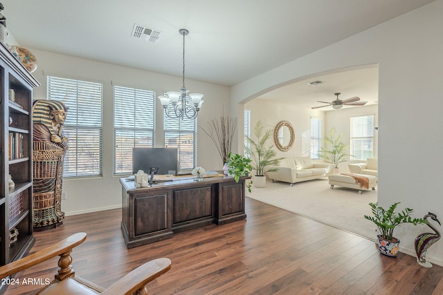 home office featuring plenty of natural light, dark wood-type flooring, and ceiling fan with notable chandelier