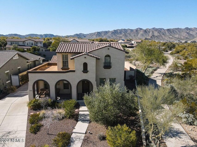 mediterranean / spanish-style home with a mountain view, concrete driveway, a tiled roof, a residential view, and stucco siding