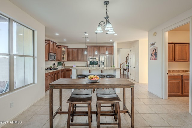 kitchen featuring an inviting chandelier, light tile patterned floors, light stone countertops, appliances with stainless steel finishes, and decorative light fixtures