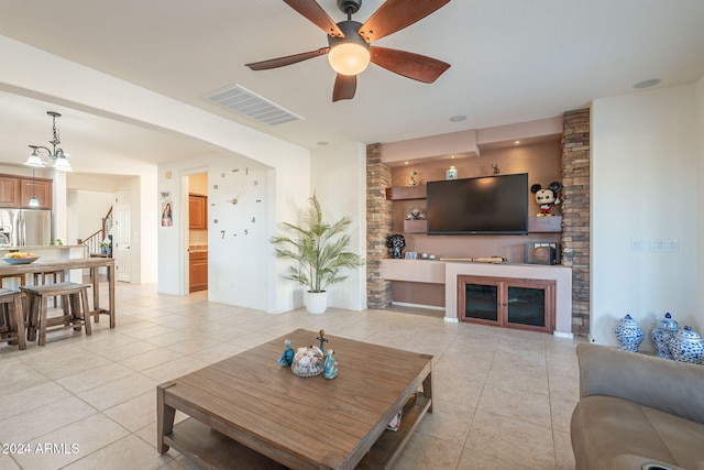 living room featuring a glass covered fireplace, visible vents, stairway, and light tile patterned flooring