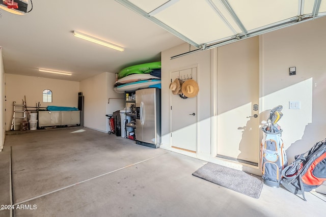 garage with stainless steel fridge and a garage door opener