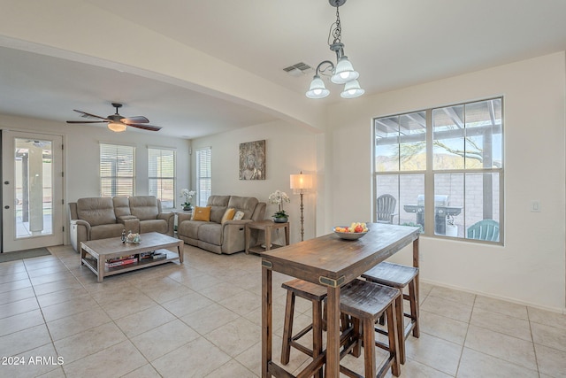 dining space featuring arched walkways, light tile patterned floors, visible vents, baseboards, and ceiling fan with notable chandelier