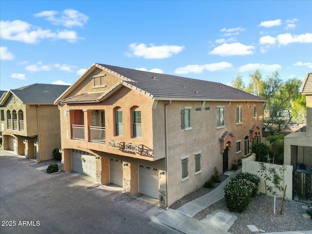 view of front of property with an attached garage, a tile roof, and stucco siding