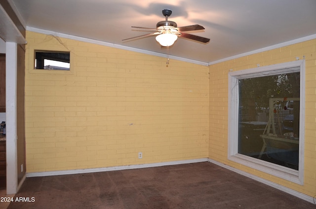 carpeted spare room featuring crown molding, ceiling fan, lofted ceiling, and brick wall