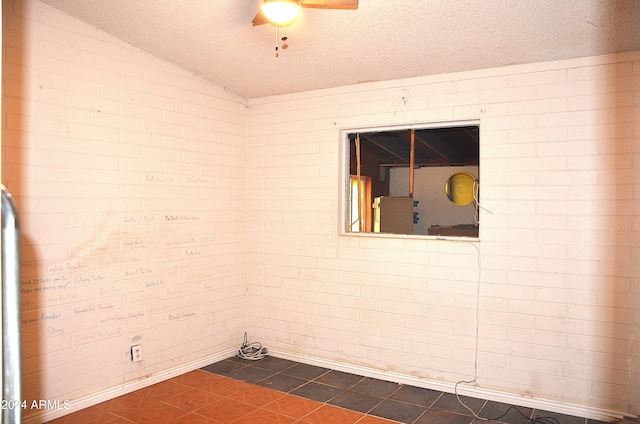 655 W Caroline St, Coolidge, AZ 85128 - unfurnished room with lofted ceiling, dark tile patterned flooring, ceiling fan, a textured ceiling, and brick wall