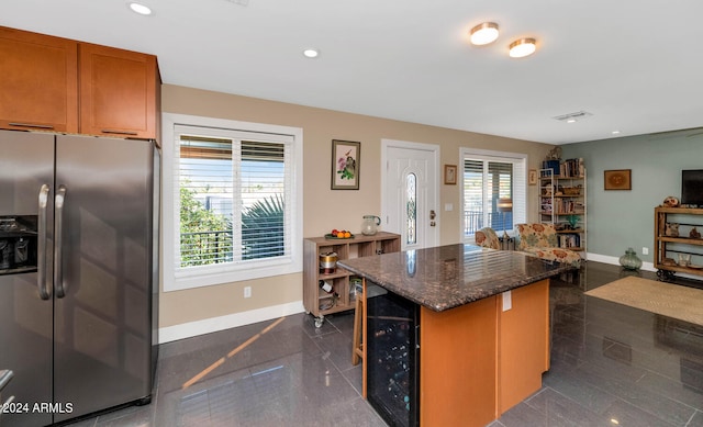 kitchen featuring beverage cooler, a wealth of natural light, a kitchen island, and stainless steel fridge