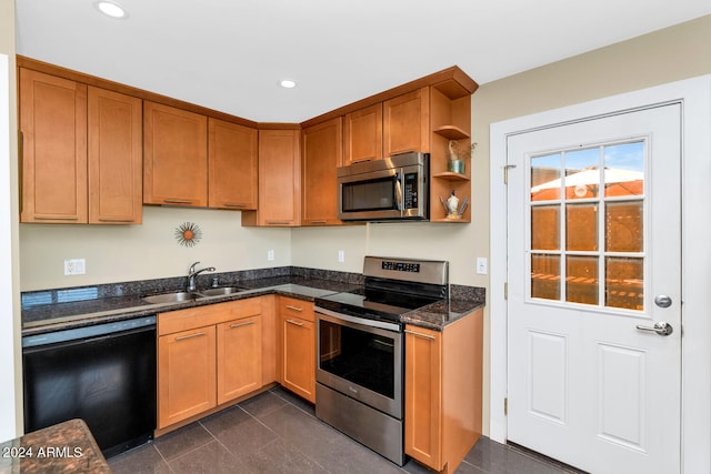 kitchen with dark tile patterned flooring, appliances with stainless steel finishes, sink, and dark stone counters