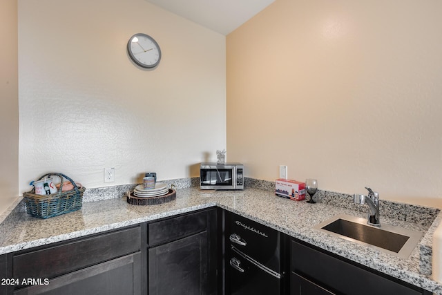 kitchen with light stone counters, sink, and vaulted ceiling