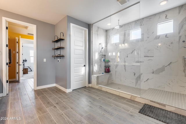 bathroom with a tile shower and a healthy amount of sunlight