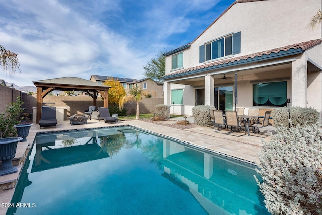 rear view of house featuring a gazebo, a fenced in pool, ceiling fan, and a patio area