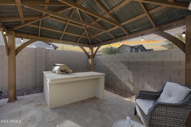 patio terrace at dusk featuring a gazebo and exterior kitchen