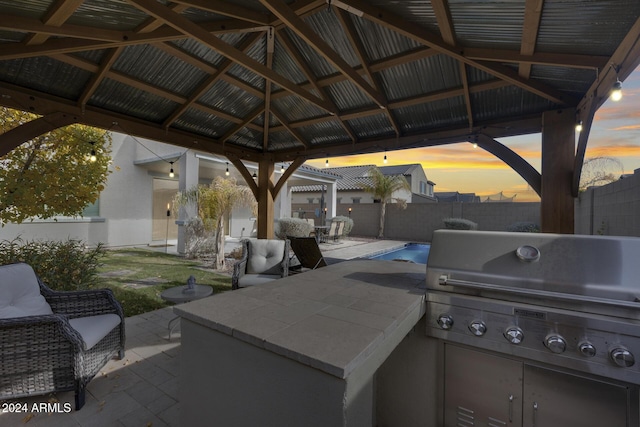 patio terrace at dusk featuring a gazebo and a grill