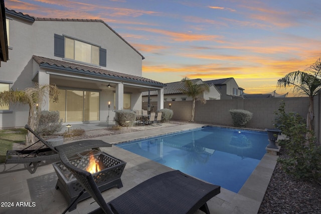 pool at dusk featuring a patio and a fire pit