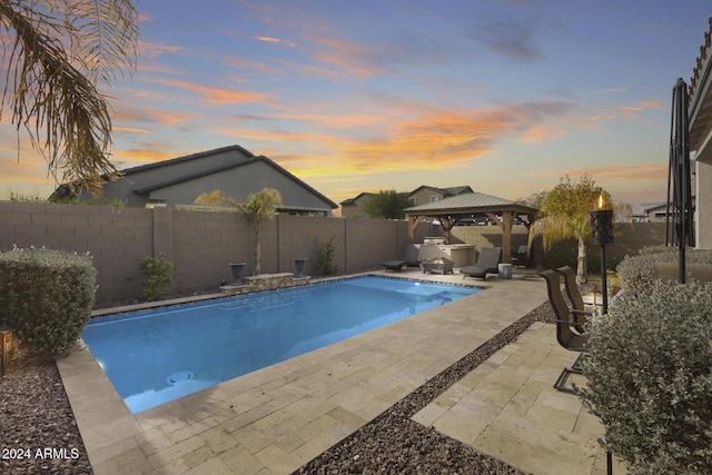 pool at dusk featuring a gazebo and a patio area