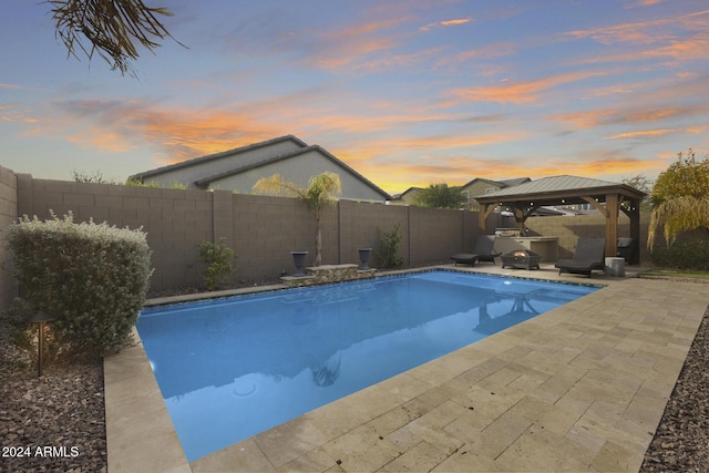 pool at dusk with a gazebo and a patio area