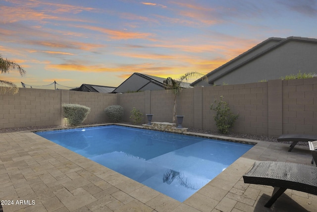 pool at dusk with a patio area