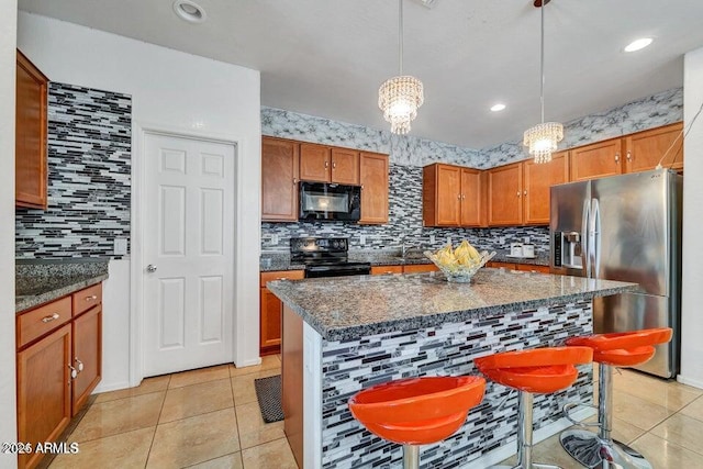 kitchen featuring light tile patterned floors, a kitchen breakfast bar, a kitchen island, pendant lighting, and black appliances