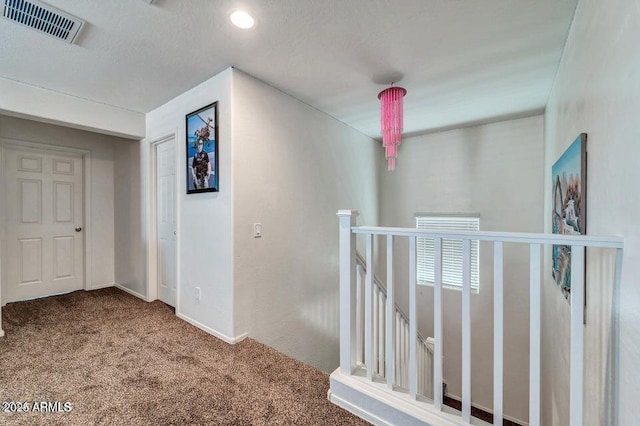 hallway with a textured ceiling and carpet