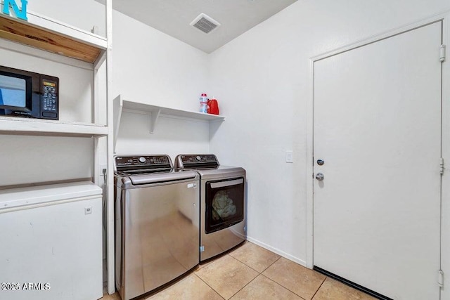 laundry area featuring washing machine and dryer and light tile patterned flooring