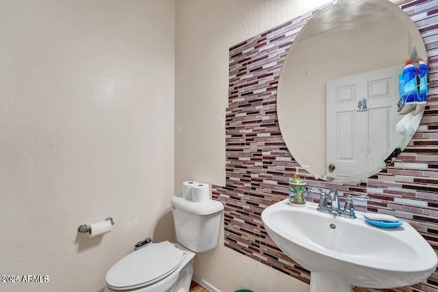 bathroom featuring tasteful backsplash, sink, and toilet