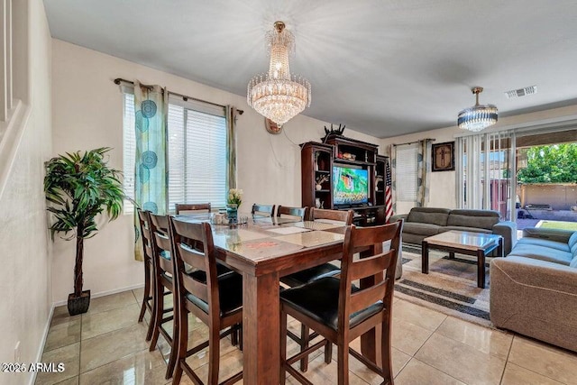 dining space with light tile patterned flooring and an inviting chandelier