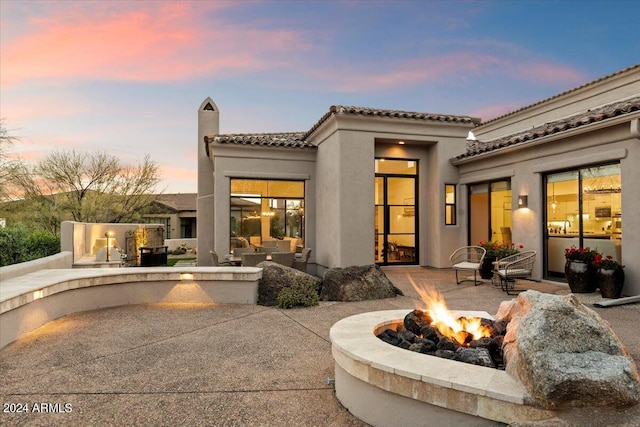 back house at dusk with a patio area and an outdoor fire pit