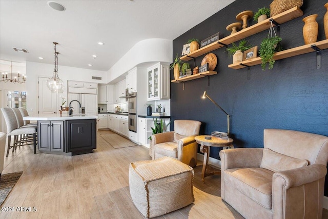 living room featuring light hardwood / wood-style floors, sink, and a chandelier